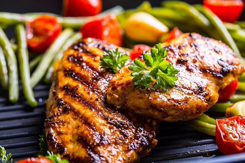 closeup of grilled chicken breasts and herbs