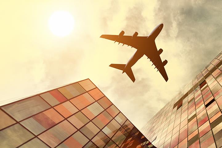 ground view of airplane flying over multistory building
