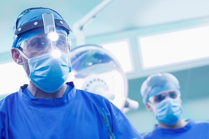 surgeon in blue wearing headlamp in operating room