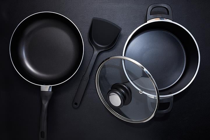 top view of a black frying pan stock pot lid and spatula
