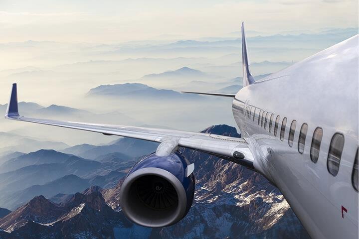 Passenger airplane flying over snow-covered mountains, showcasing Teflon™’s application in aerospace durability