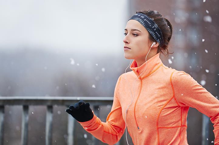 woman wearing jacket gloves hat jogging in winter weather